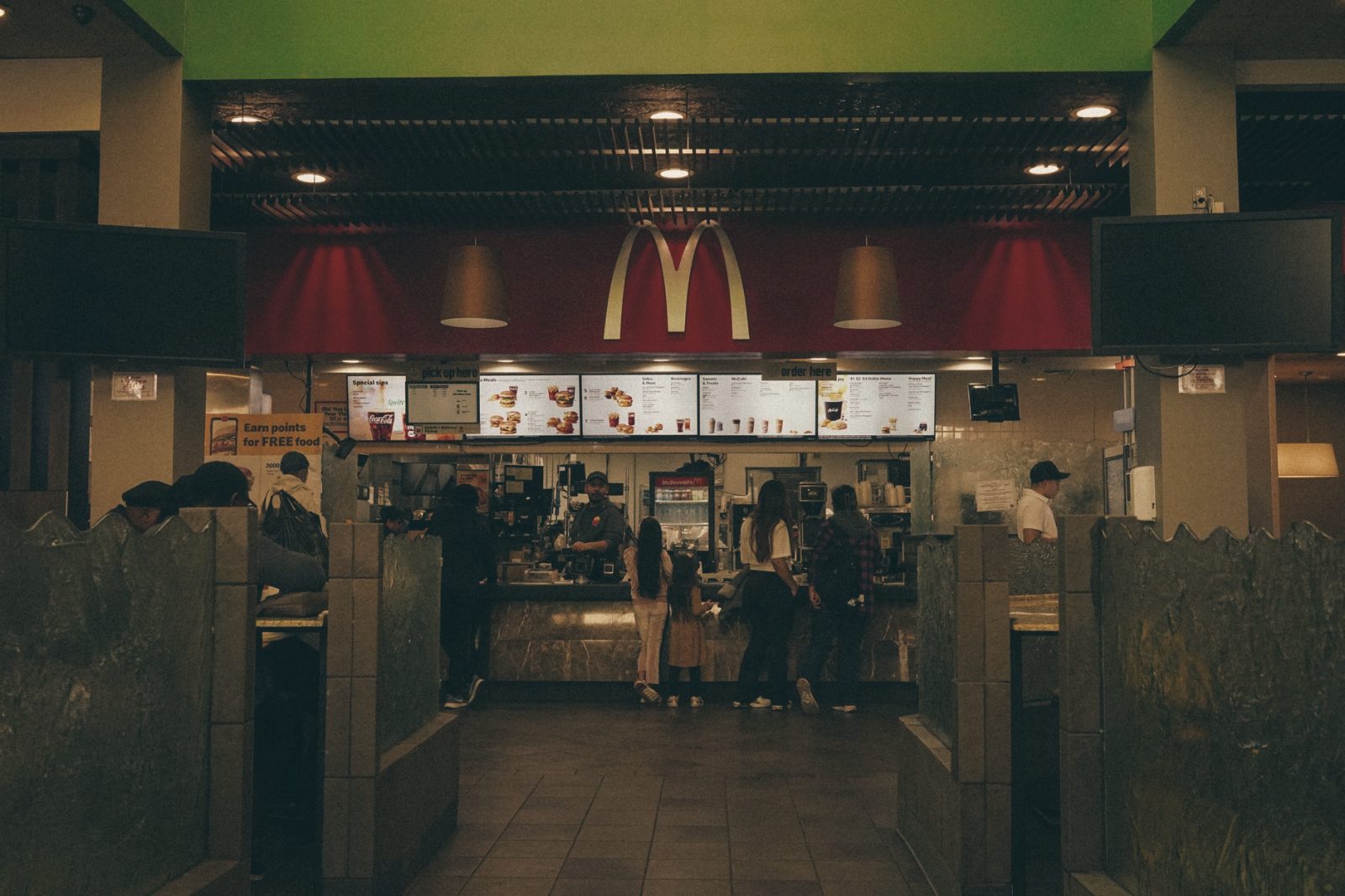 A bustling scene at a McDonald's restaurant counter with customers and staff in an indoor setting.