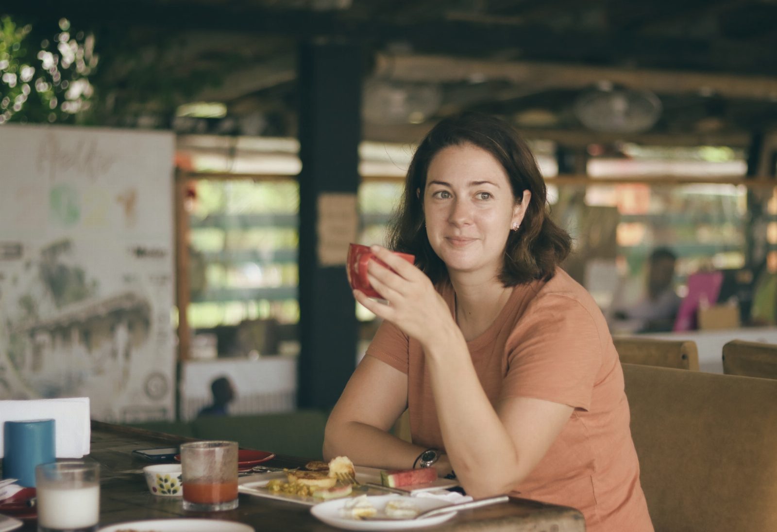 A woman with brown hair enjoys a drink at a cozy indoor café, exuding leisure and comfort.